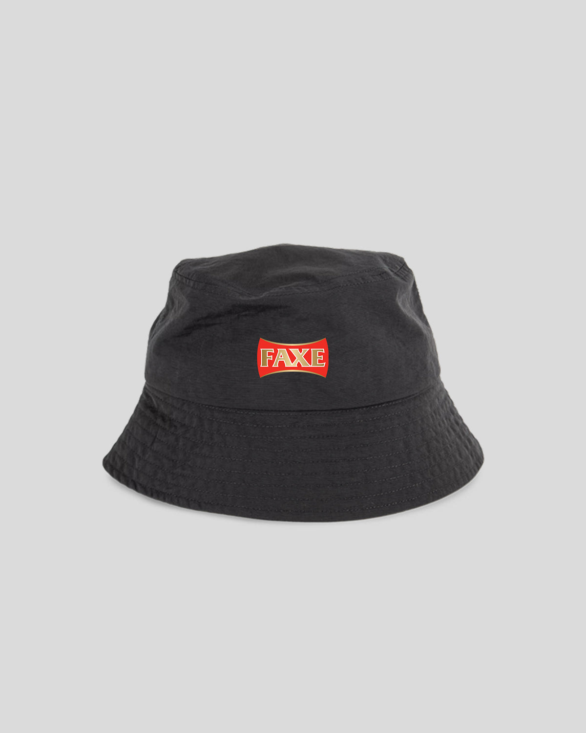 A black bucket hat with a red and white 'FAKE' logo patch on the front, photographed against a solid light gray background.
