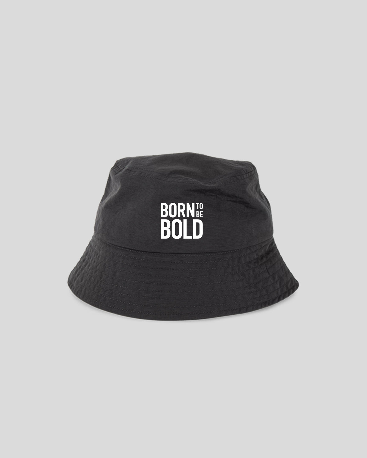 A black bucket hat with the phrase 'BORN TO BE BOLD' printed in white block letters on the front, set against a solid light gray background.